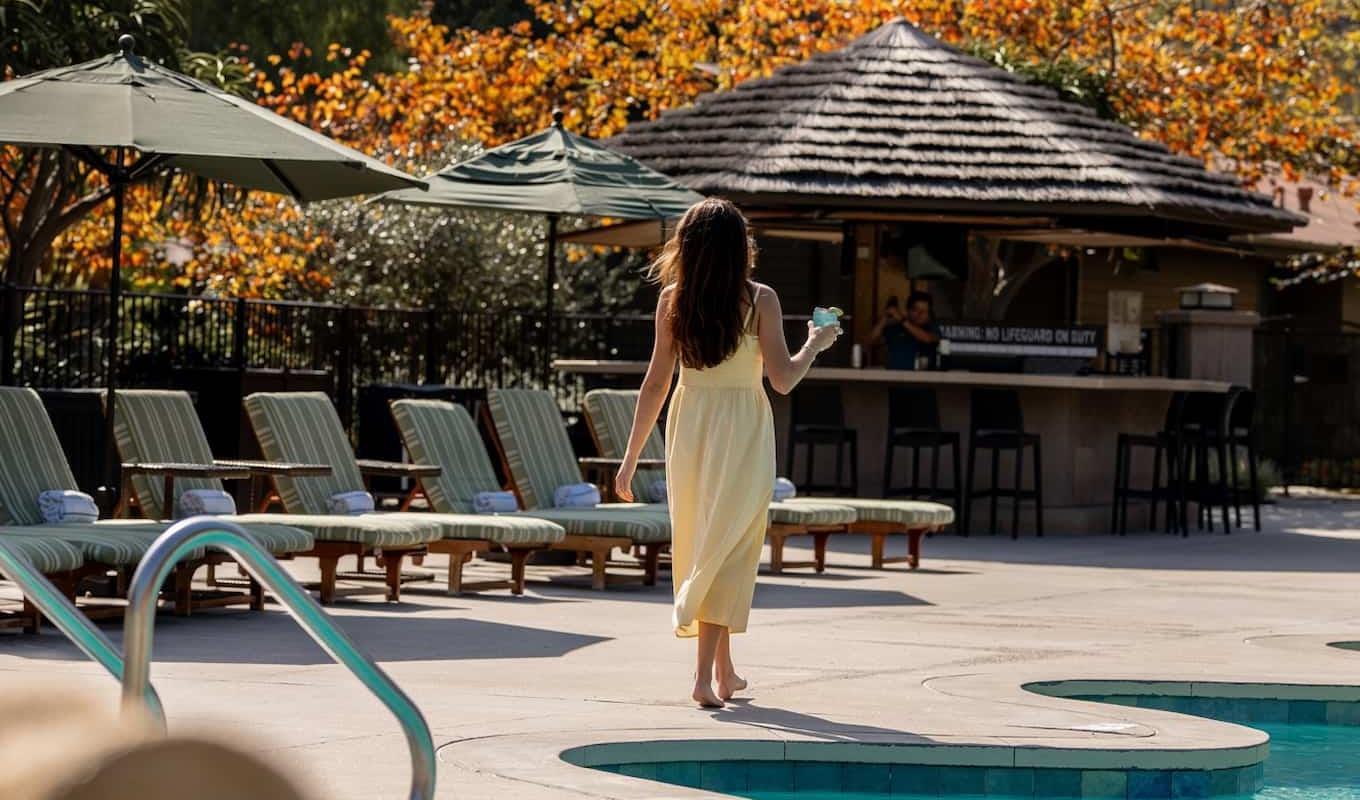 Woman walking by pool with a drink in her hand