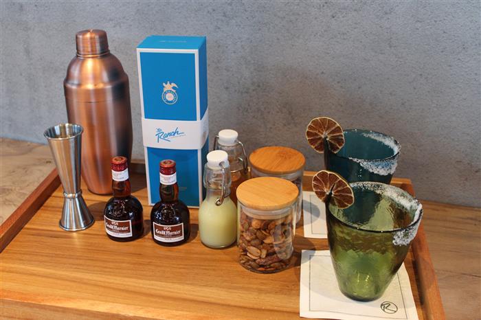 A bottle of Casa Dragones Tequila, mixed nuts and ingredients on a table